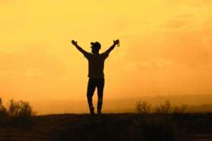 Silhouette of person celebrating at sunset
