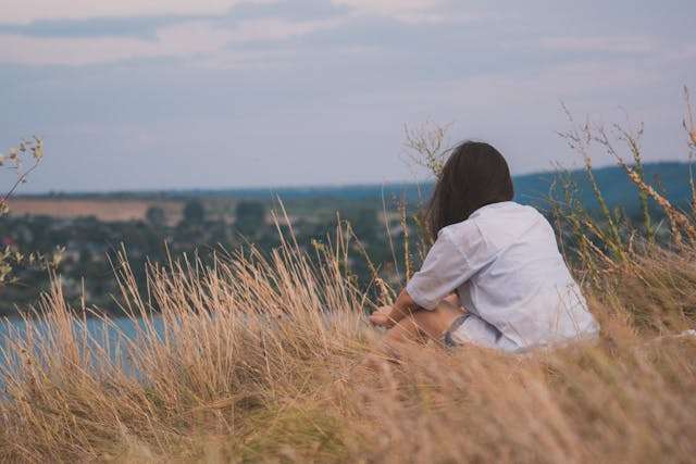 Person sitting on grassy hilltop