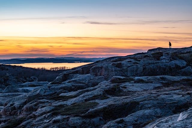 Person standing on rocky landscape at sunset