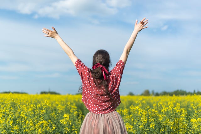 Woman celebrating in yellow flower field