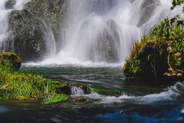 A stunning waterfall cascading over moss-covered rocks in a lush forest setting.