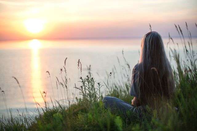 Person sitting by serene sunset
