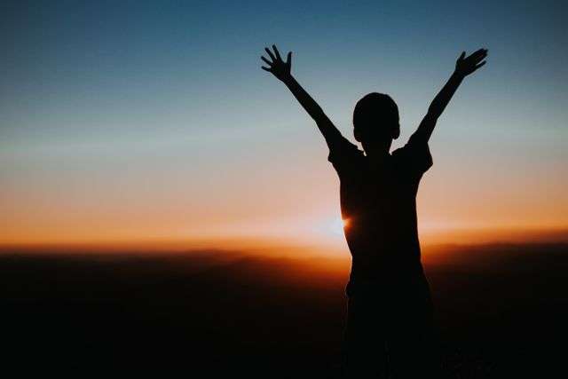 Child silhouetted against sunset sky