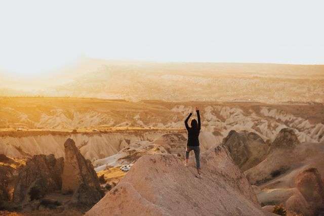 Person celebrating on a rocky landscape.